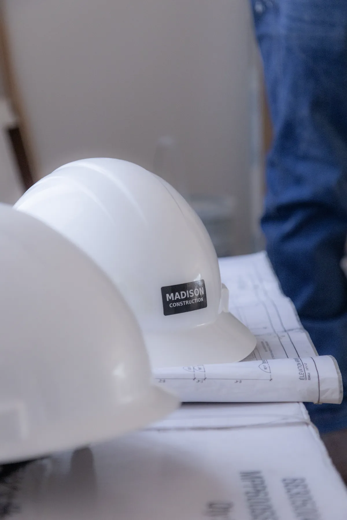 Casque de chantier Madison Construction posé sur des plans de construction